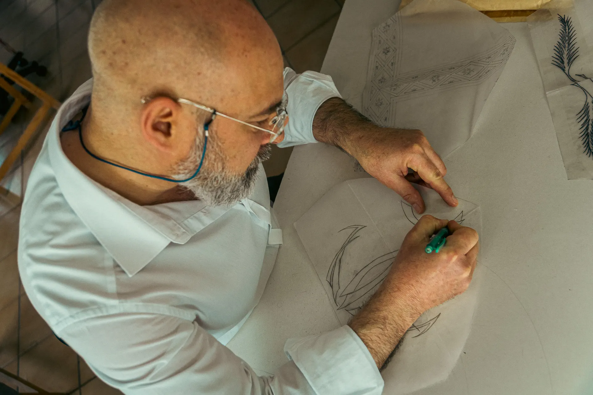 Michele Cassata disegna a mano il tracciato di un ricamo su carta