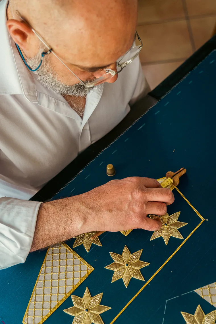 Michele Cassata ricama a mano stelle in oro su un paramento blu