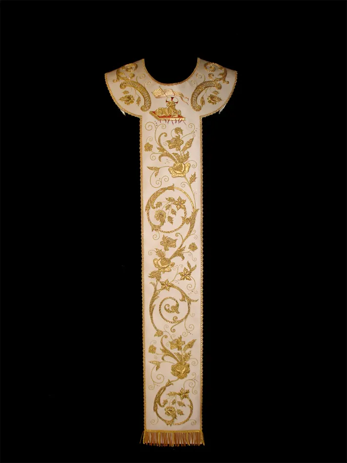 Pallio ricamato in oro su moella di seta color avorio. Il pallio nasce dal riporto di una serie di elementi che certamente facevano parte di un parato che è stato smembrato qualche decennio addietro. Gli elmenti rimasti sono stati ricomposti, lucidati, restaurati ed integrati con parti nuove ed hanno dato vita a questo ricco ed esuberante pallio che orna le casule nei vari colori liturgici.
